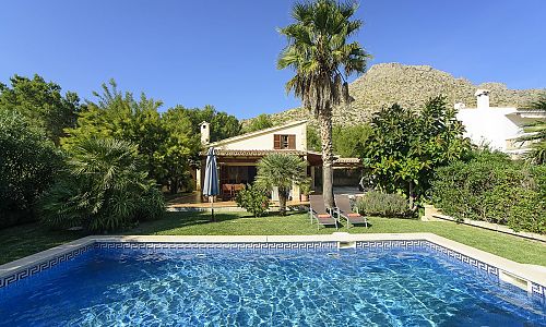 Poolbereich vor der Finca im Garten mit Rasen und Bäumen