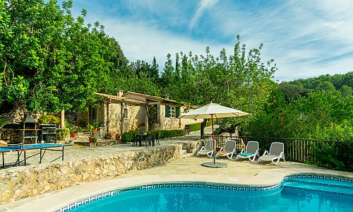 Poolbereich vor der Finca mit Bäumen und Sonnenliegen