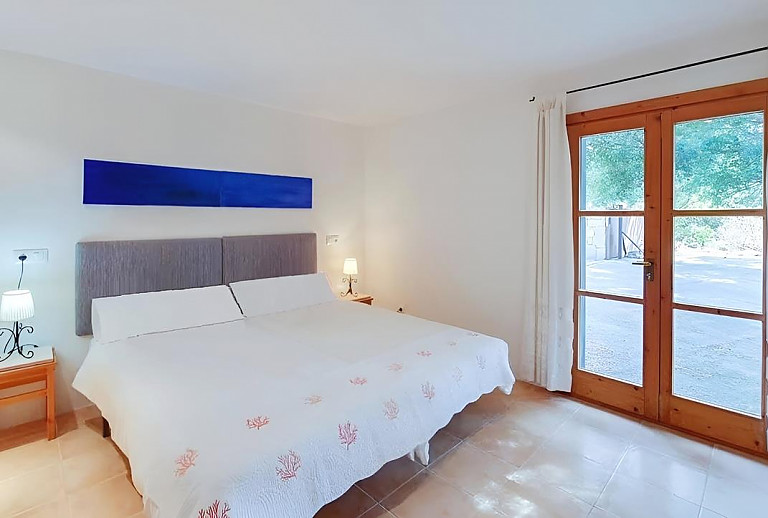 Schlafzimmer mit Doppelbett und Zugang zum Außenbereich