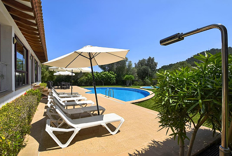 Terrasse mit Poolliegen und Rasenfläche