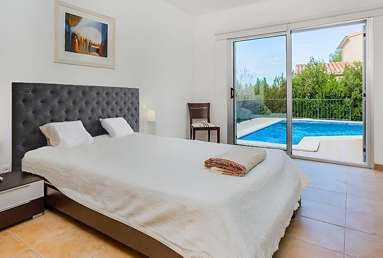 Schlafzimmer mit Doppelbett und Poolblick