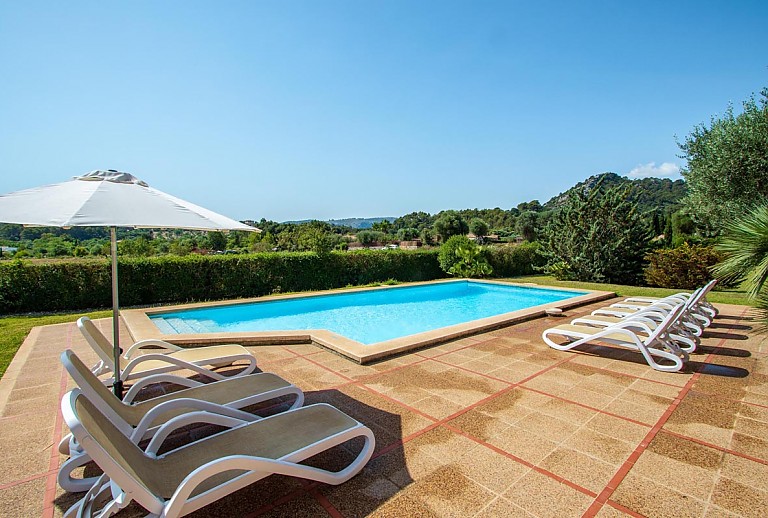 Poolbereich mit Sonnenliegen und Sonnenschirm