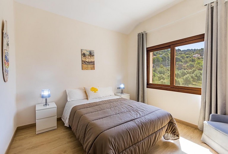 Doppelbett im Schlafzimmer mit Fenster und Bild an der Wand