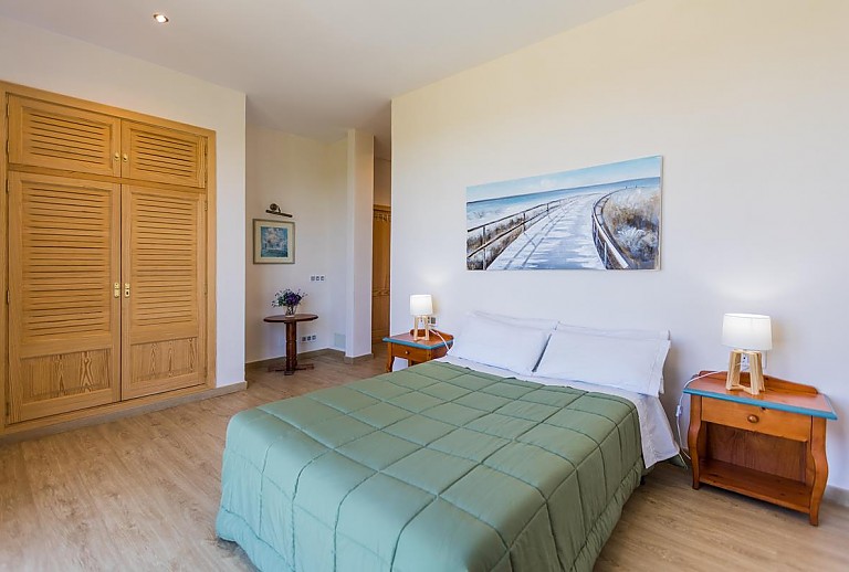 Doppelbett im Schlafzimmer mit Wandbild und Wandschrank