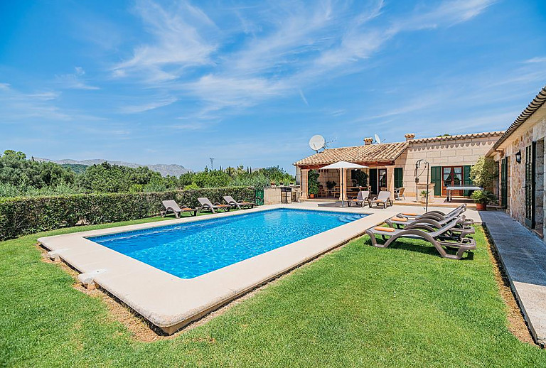 Poolbereich vor der Finca mit Rasenfläche und Sonnenliegen