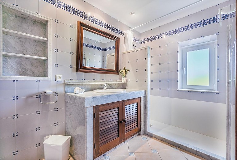 Badezimmer mit Dusche Waschbecken und Spiegel