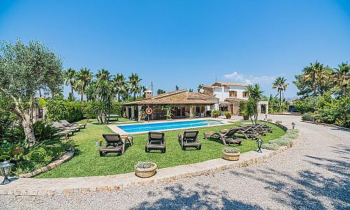 Poolbereich mit Sonnenliegen und Rasenfläche vor der Finca