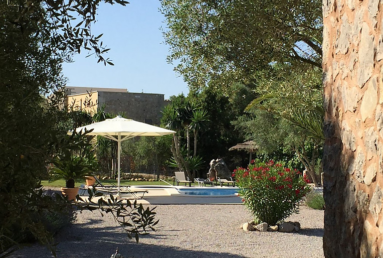 Poolbereich vor der Finca mit Sonnenschirm und Bäumen