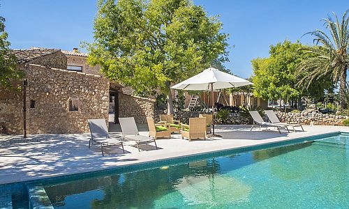 Pool mit Sonnenliegen und Sonnenschirm vor der Finca