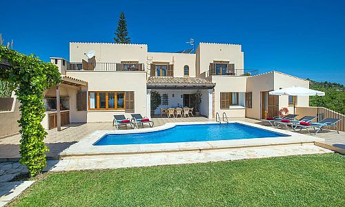 Poolbereich mit Rasen und Poolliegen vor der Finca