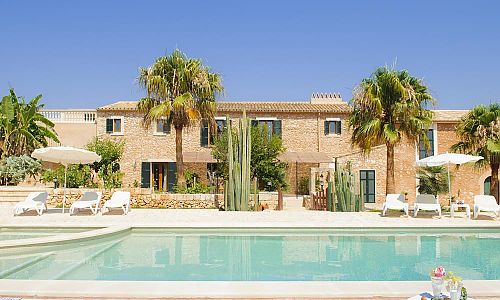 Poolbereich vor der Finca mit Palmen und Sonnenschirmen