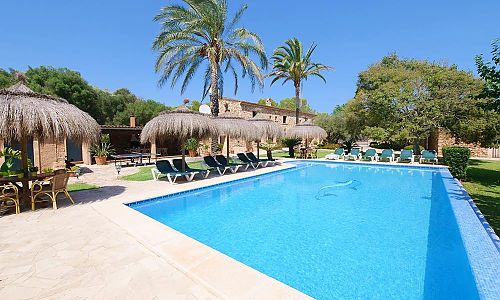Pool mit Sonnenliegen und Sonnenschirmen vor dem Ferienhaus