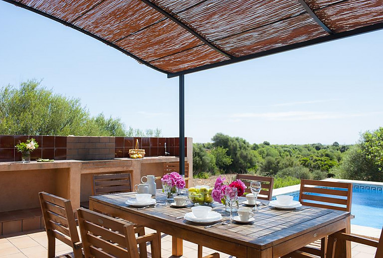 Terrasse mit Esstisch und Poolblick