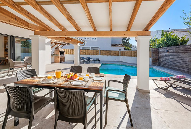 Terrasse mit Esstisch und Poolblick