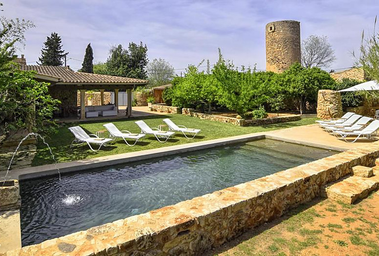 Rasen und Sonnenliegen am Pool vor der Finca