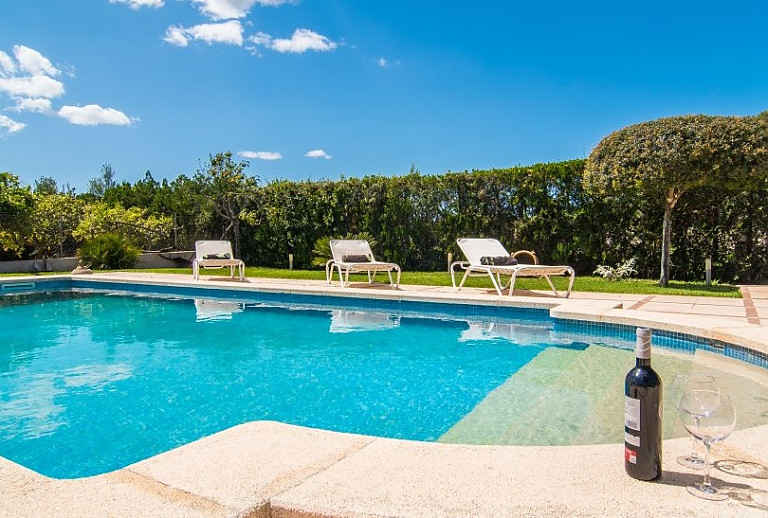 Rasen am Pool mit Sonnenliegen vor der Finca