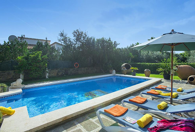 Sonnenliegen und Sonnenschirm am Pool vor der Finca