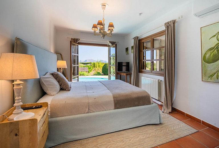 Schlafzimmer mit Doppelbett und Zugang zur Poolterrasse