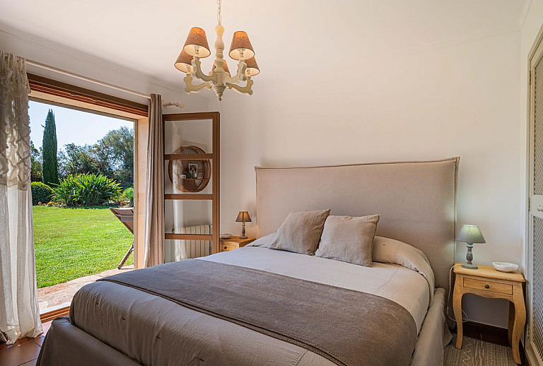 Schlafzimmer mit Doppelbett und Zugang zum Garten