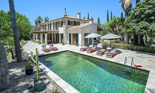 Poolbereich mit Sonnenliegen und Sonnenschirm vor der Finca