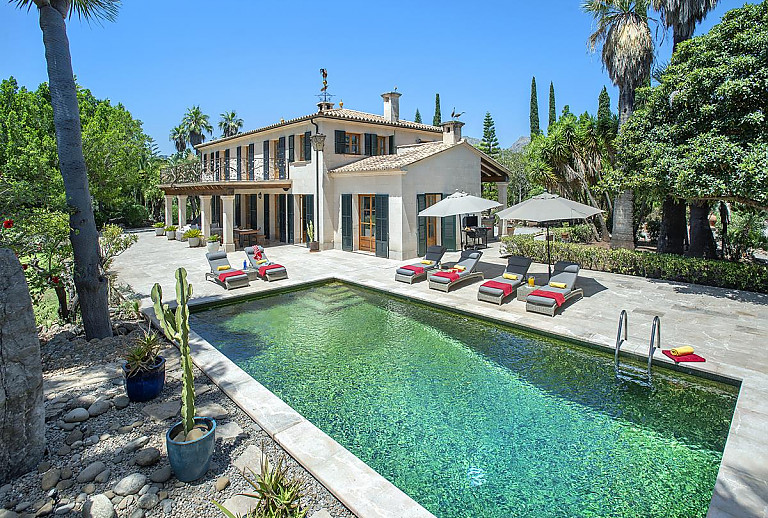 Poolbereich mit Sonnenliegen und Sonnenschirm vor der Finca