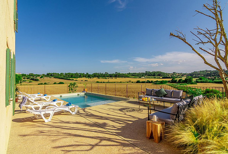 Poolterrasse mit Sitzmöbeln und Sonnenliegen