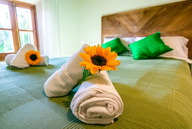 Doppelbett mit Handtüchern und Blumen
