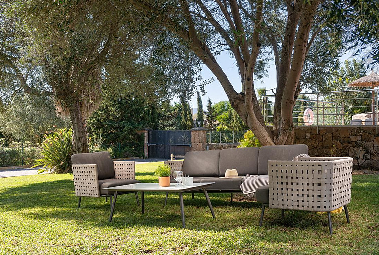 Gartenmöbel auf dem Rasen im Schatten der Bäumen