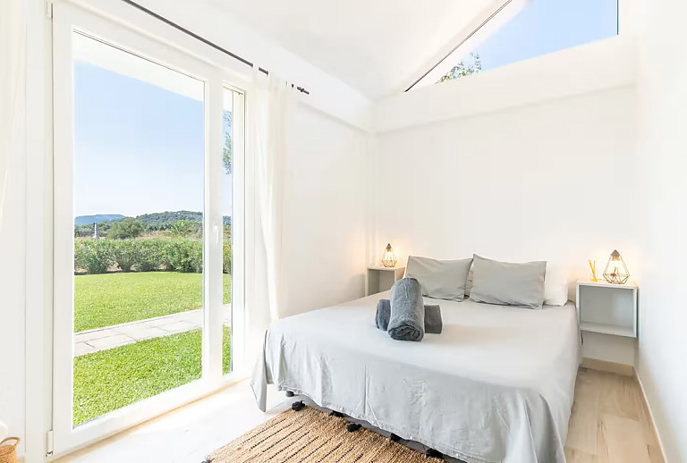 Schlafzimmer mit Doppelbett und Zugang zum Garten